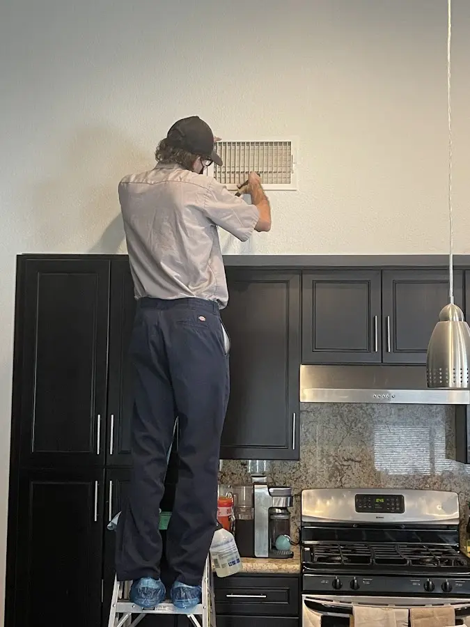 Technician inspecting an air vent during HVAC service in Brewer